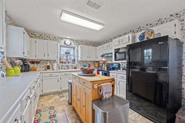 kitchen featuring tasteful backsplash, white cabinets, black appliances, a textured ceiling, and wall chimney exhaust hood