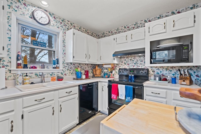 kitchen with white cabinetry, sink, wall chimney range hood, and black appliances