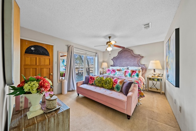 bedroom featuring ceiling fan, light colored carpet, and a textured ceiling