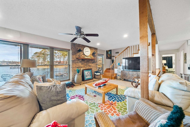 living room with ceiling fan, a brick fireplace, and a textured ceiling