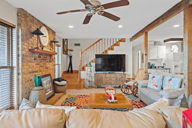 living room with ceiling fan, beam ceiling, and a brick fireplace