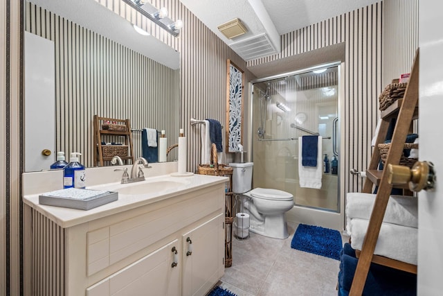 bathroom featuring tile patterned flooring, vanity, a textured ceiling, toilet, and walk in shower