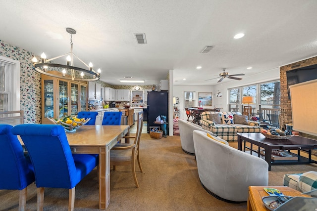 dining space with light carpet, ceiling fan with notable chandelier, and a textured ceiling