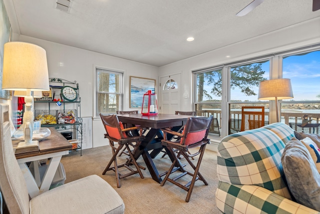 dining space featuring light colored carpet and a textured ceiling