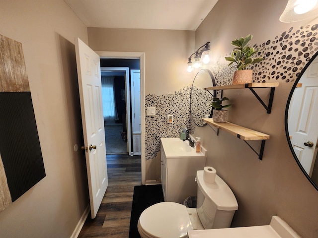 half bathroom featuring toilet, baseboards, wood finished floors, and vanity