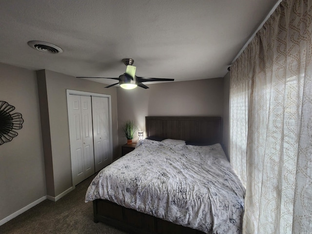 bedroom featuring a textured ceiling, visible vents, baseboards, a closet, and dark colored carpet