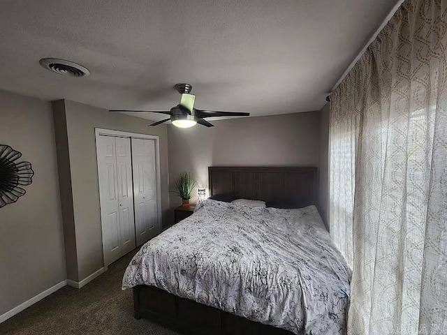 bedroom with a textured ceiling, visible vents, a ceiling fan, a closet, and dark colored carpet