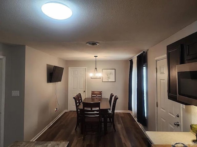 dining area with a textured ceiling, dark wood finished floors, visible vents, and baseboards