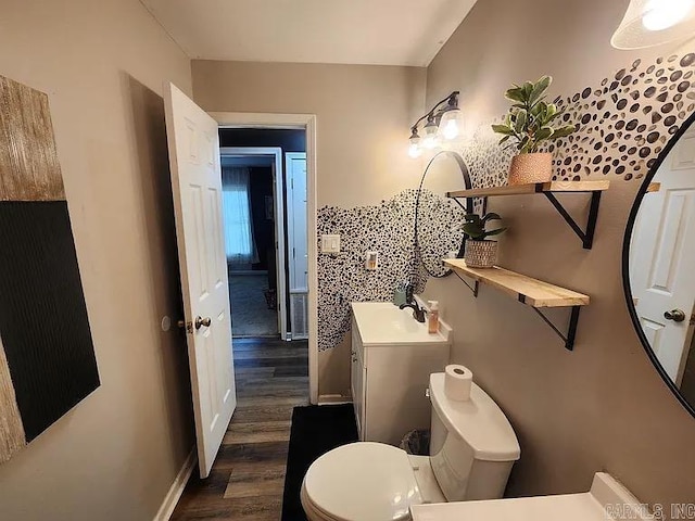 bathroom featuring toilet, baseboards, wood finished floors, and vanity