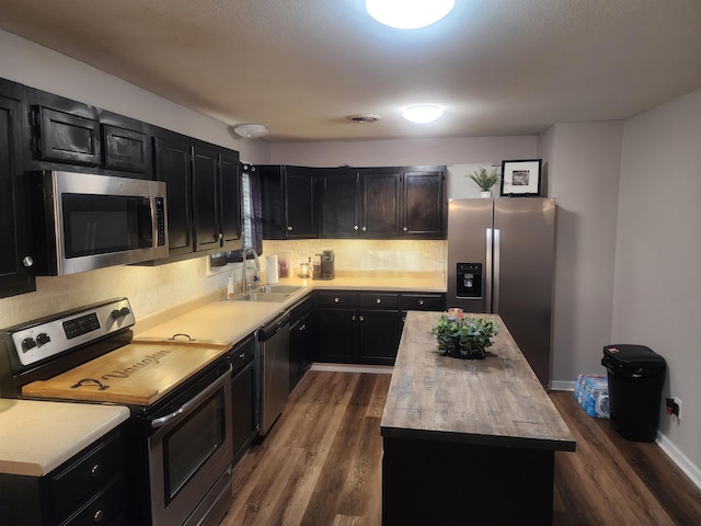 kitchen featuring dark wood-style floors, butcher block counters, appliances with stainless steel finishes, dark cabinets, and a sink