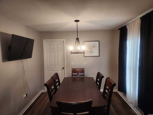 dining area featuring a chandelier, dark wood finished floors, and baseboards