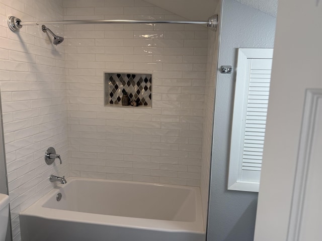 bathroom with toilet and tiled shower / bath