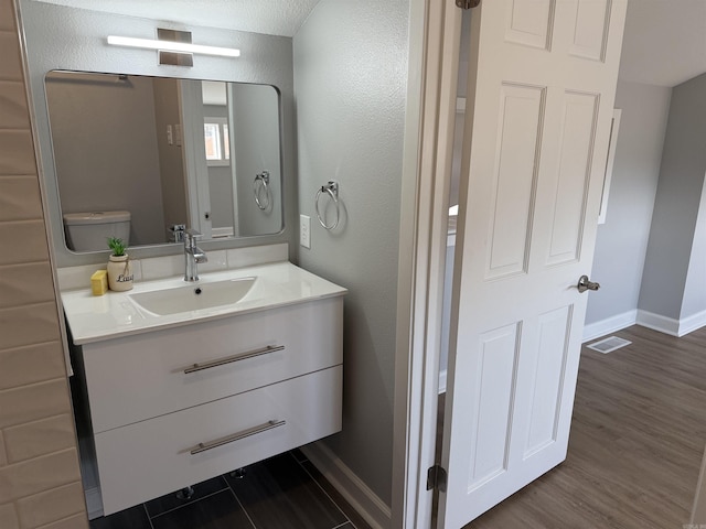 bathroom with vanity, hardwood / wood-style flooring, and toilet