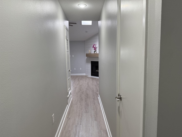 hallway with a textured ceiling and light wood-type flooring