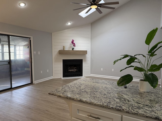 living room with hardwood / wood-style flooring, a large fireplace, ceiling fan, and vaulted ceiling