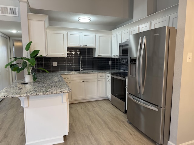 kitchen with sink, a breakfast bar area, white cabinetry, appliances with stainless steel finishes, and kitchen peninsula