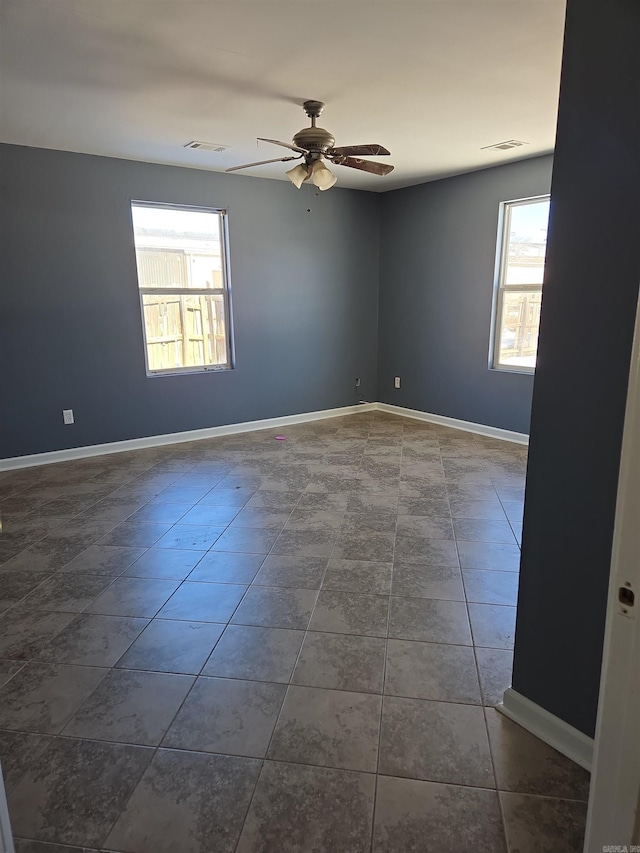 unfurnished room featuring ceiling fan and dark tile patterned floors