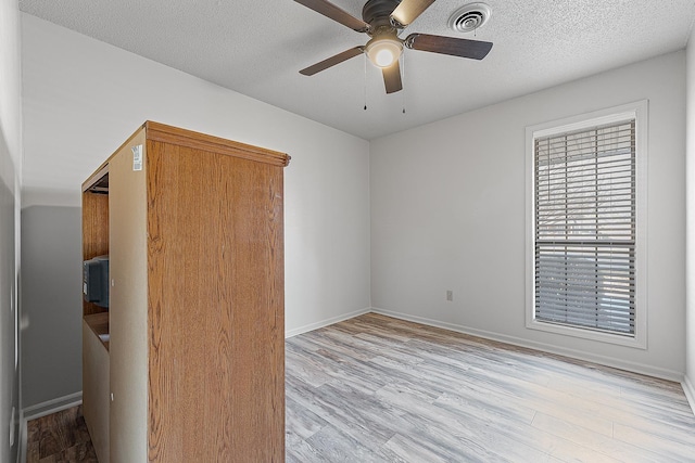 unfurnished bedroom featuring a textured ceiling, light hardwood / wood-style floors, and ceiling fan