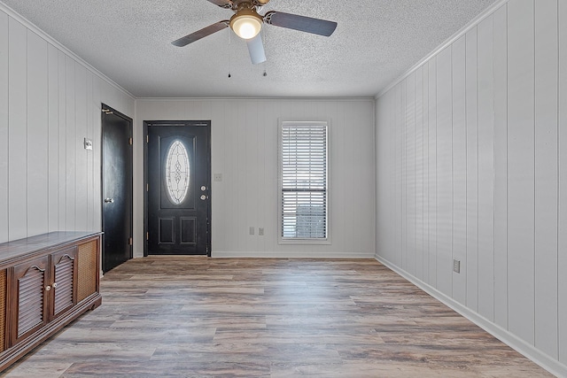 foyer with crown molding, ceiling fan, wooden walls, and light hardwood / wood-style flooring