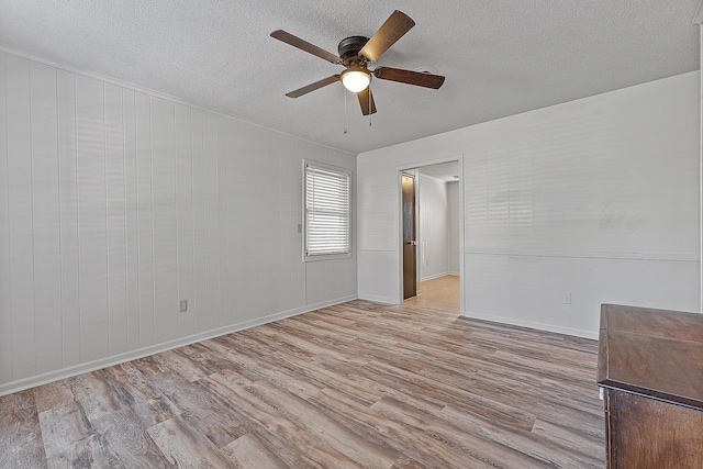 spare room with ceiling fan, light hardwood / wood-style flooring, and a textured ceiling