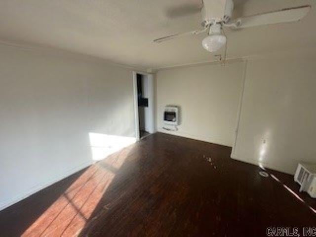 spare room featuring ceiling fan, dark hardwood / wood-style floors, and heating unit