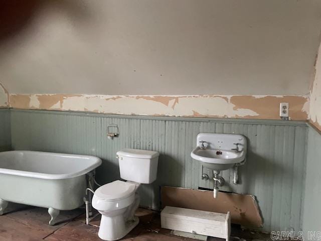 bathroom with a tub, wooden walls, and toilet