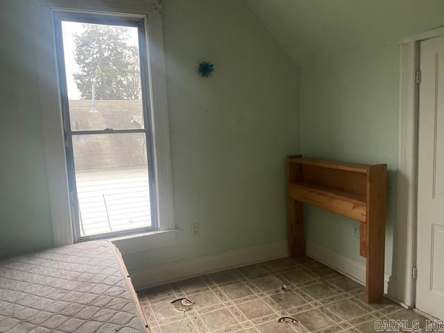 unfurnished bedroom featuring multiple windows and lofted ceiling