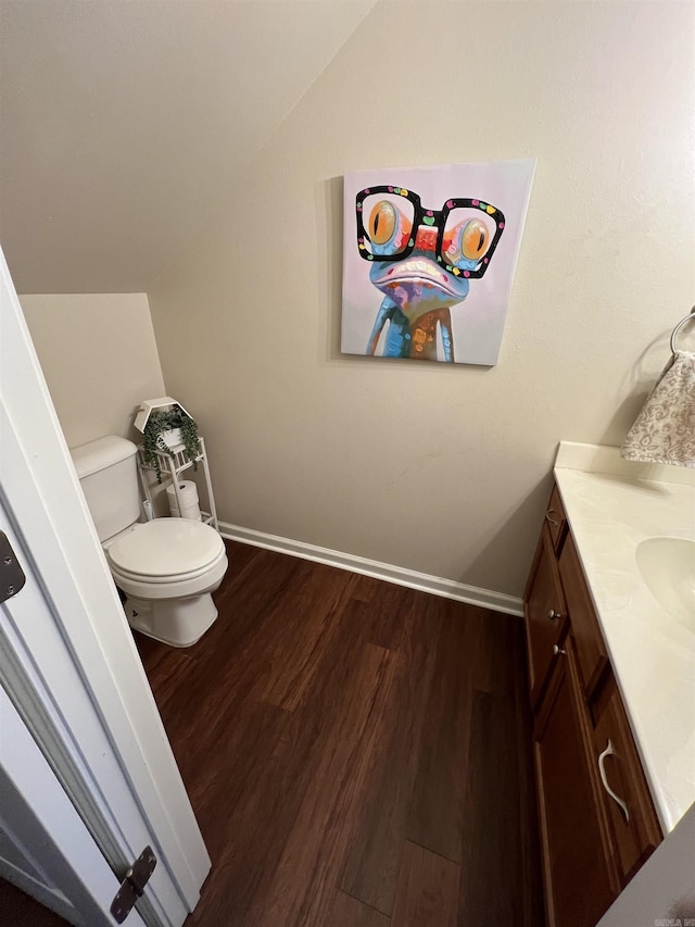 bathroom featuring hardwood / wood-style flooring, lofted ceiling, vanity, and toilet