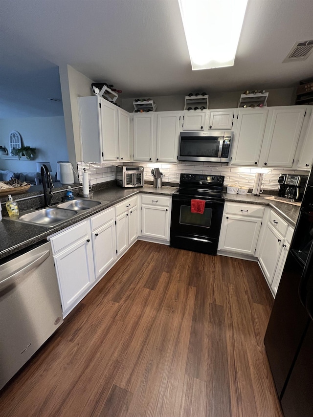 kitchen featuring sink, white cabinetry, appliances with stainless steel finishes, dark hardwood / wood-style floors, and backsplash