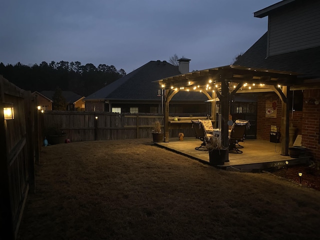 yard at dusk with a pergola, a jacuzzi, and a deck