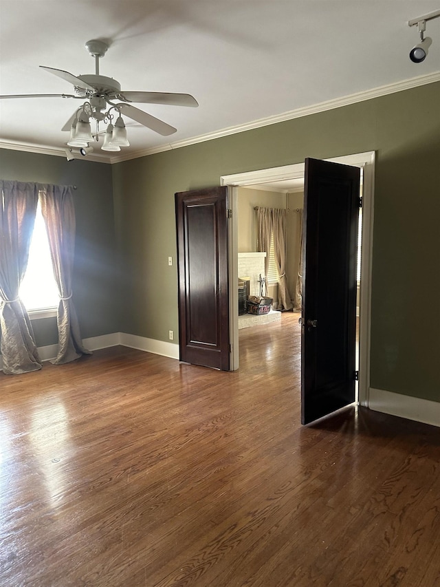 spare room featuring ceiling fan, ornamental molding, hardwood / wood-style floors, and a brick fireplace