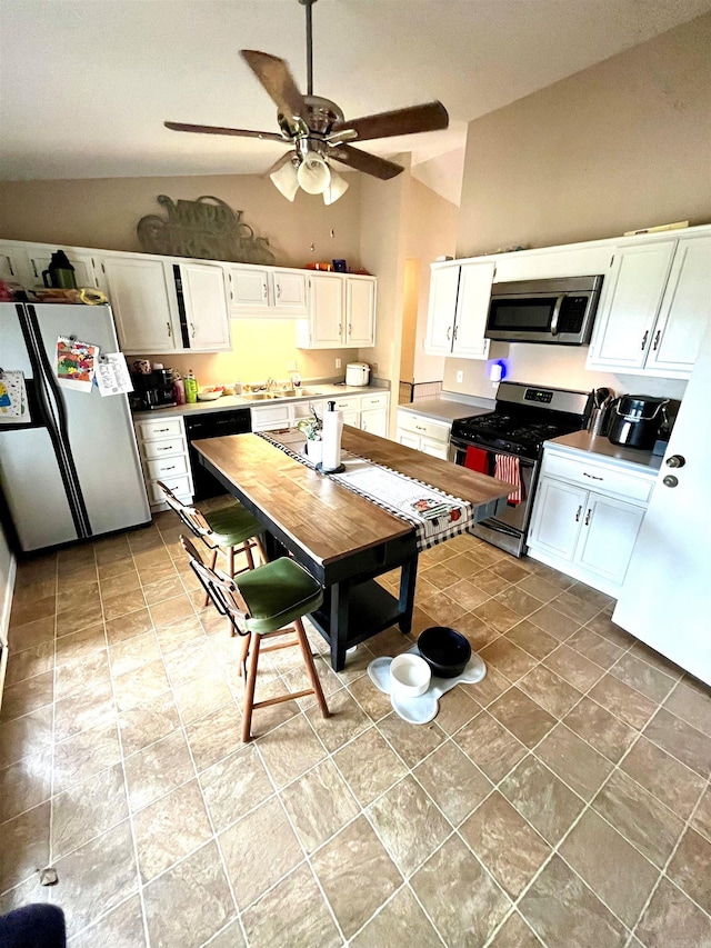 kitchen featuring lofted ceiling, white cabinetry, stainless steel appliances, and ceiling fan