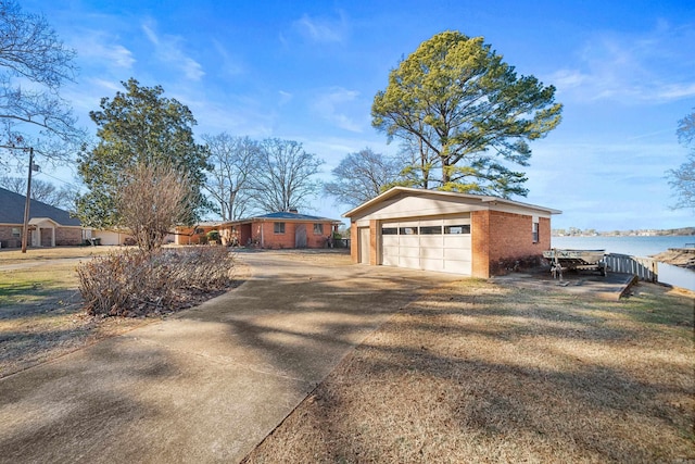 view of property exterior with a garage, a water view, and an outdoor structure