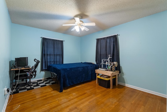 bedroom with a textured ceiling, ceiling fan, and hardwood / wood-style flooring