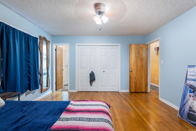 bedroom with a textured ceiling, wood-type flooring, a closet, and ceiling fan