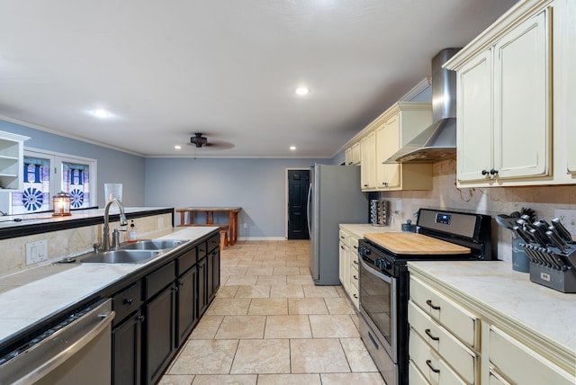 kitchen with appliances with stainless steel finishes, sink, crown molding, cream cabinets, and wall chimney exhaust hood