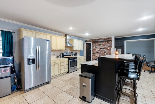 kitchen featuring stainless steel appliances, crown molding, cream cabinetry, and wall chimney exhaust hood