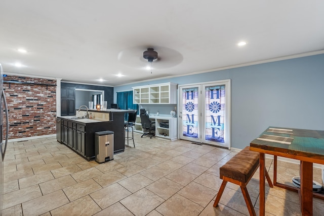 kitchen featuring sink, crown molding, an island with sink, and a kitchen bar