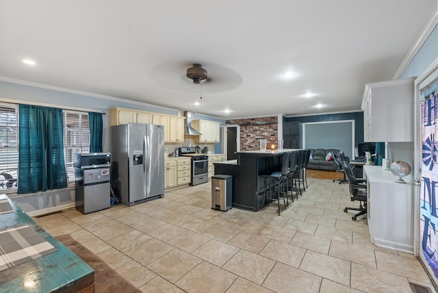 kitchen with wall chimney range hood, crown molding, ceiling fan, stainless steel appliances, and a kitchen bar