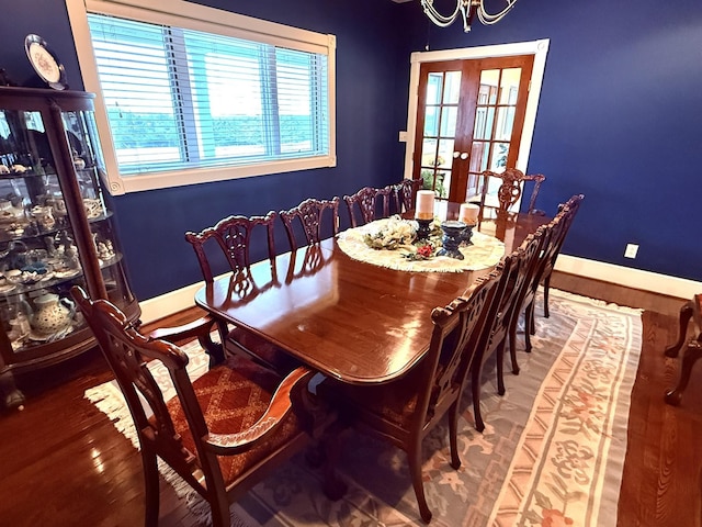 dining space featuring hardwood / wood-style flooring, a notable chandelier, and french doors