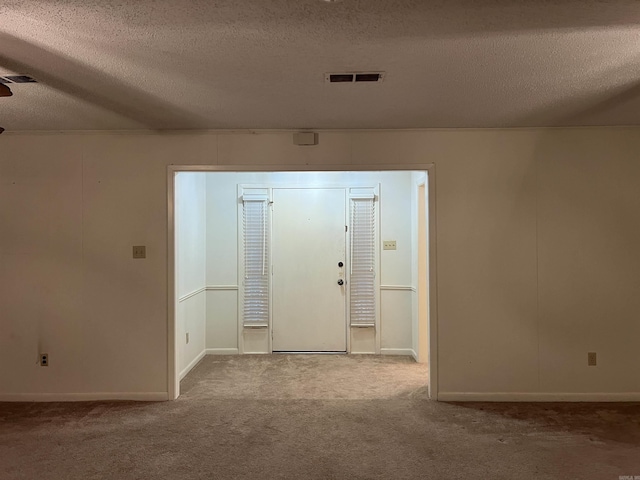 foyer entrance with carpet and a textured ceiling