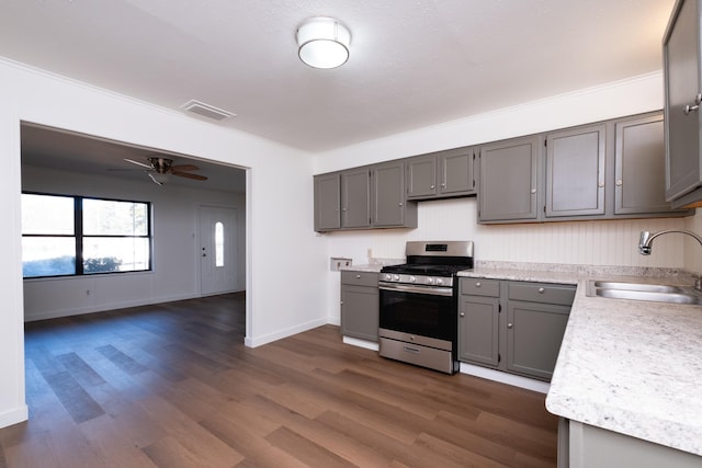 kitchen with gray cabinets, sink, ceiling fan, dark wood-type flooring, and stainless steel range with gas stovetop