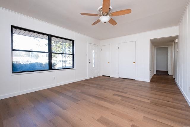 unfurnished bedroom featuring hardwood / wood-style floors, multiple closets, and ceiling fan