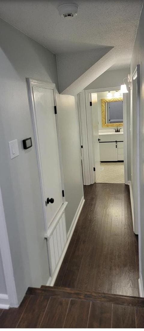 hall featuring a textured ceiling and dark hardwood / wood-style flooring