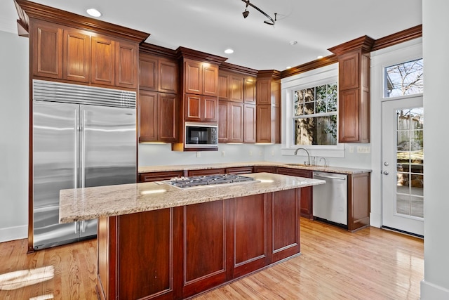 kitchen featuring light stone counters, built in appliances, light hardwood / wood-style floors, and a kitchen island