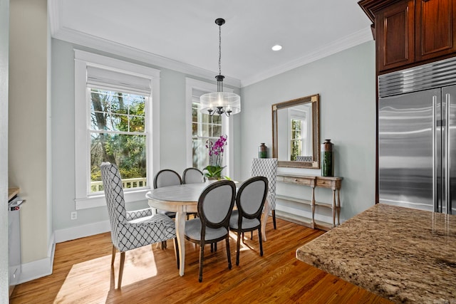 dining space with a notable chandelier, a wealth of natural light, ornamental molding, and light wood-type flooring