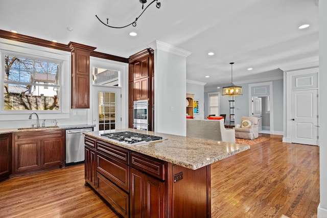 kitchen featuring a kitchen island, appliances with stainless steel finishes, sink, hanging light fixtures, and ornamental molding