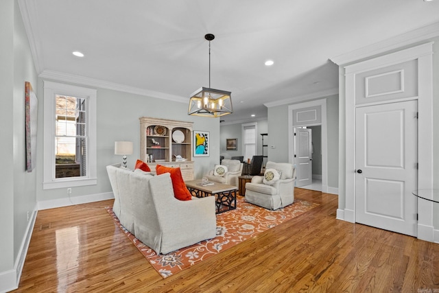 living room featuring an inviting chandelier, ornamental molding, and light hardwood / wood-style floors