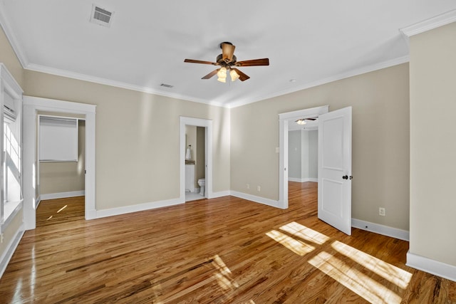 unfurnished bedroom with ensuite bathroom, crown molding, wood-type flooring, a closet, and ceiling fan