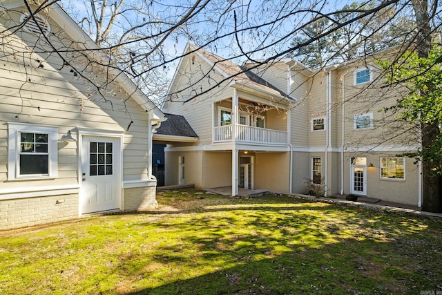 back of house with french doors, a balcony, and a lawn